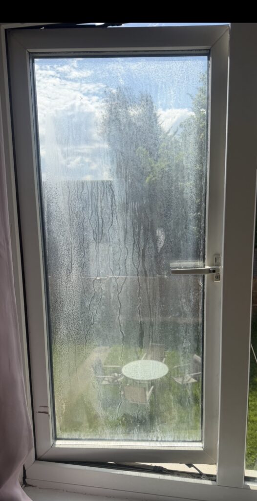 Misted double glazed window with condensation trapped between the glass panes